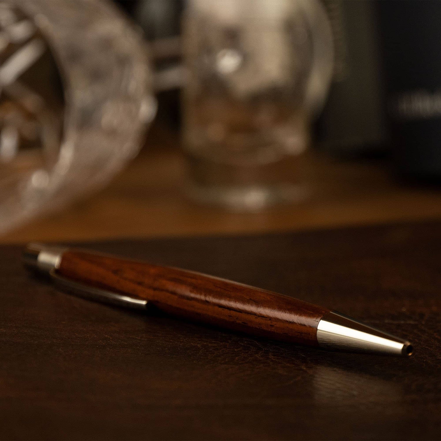 Hembo Kugelschreiber Cocobolo liegend vor einem Glas